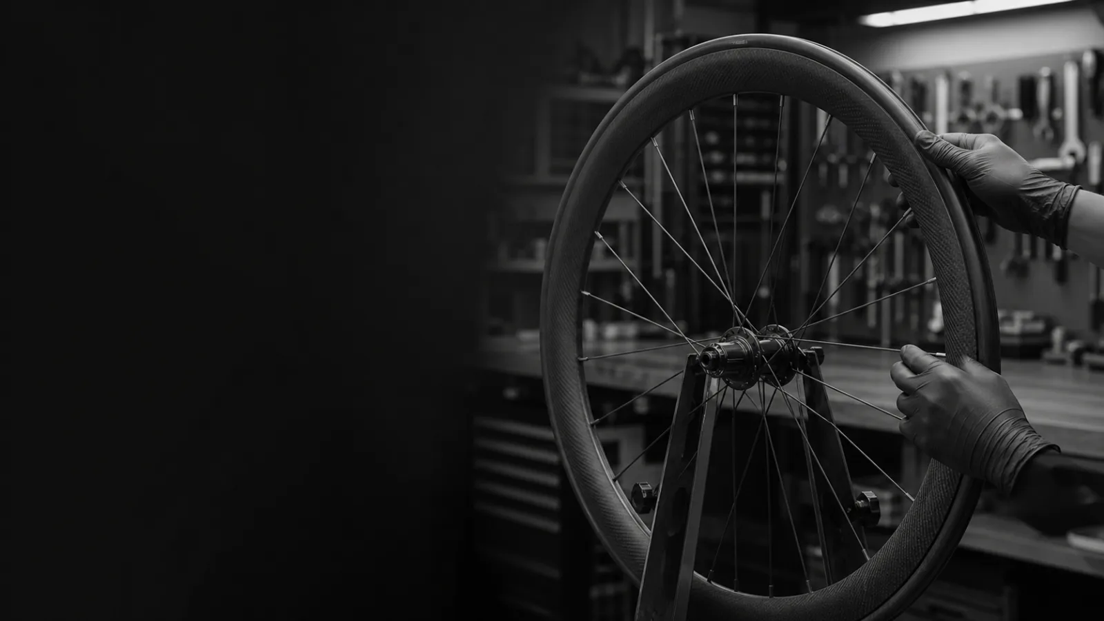 Black-gloved hands inspecting a carbon wheel in a truing stand